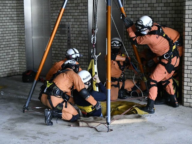 救助用の穴から救助者をつり上げる消防隊員＝各務原市役所旧庁舎