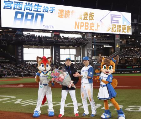 　連続救援登板のプロ野球記録を更新し記念写真に納まる日本ハム・宮西。右は郡司＝エスコンフィールド