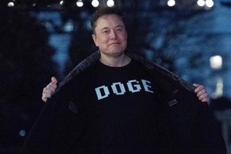 　政府効率化省を意味する「ＤＯＧＥ」の文字が書かれたＴシャツを見せるマスク氏＝３月９日、米首都ワシントン（ＡＰ＝共同）