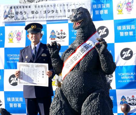 　神奈川県警横須賀南署の一日署長に委嘱された「ゴジラ」。左は小島博署長＝１０日午後、神奈川県横須賀市