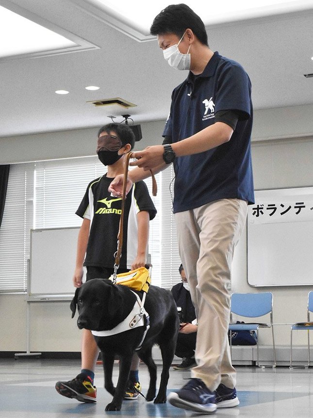 目隠しをして盲導犬と歩く体験をする児童＝海津市海津町高須、海津総合福祉会館ひまわり
