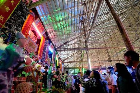 　竹で造られた建物の中で、祭りの展示にカメラを向ける人々＝１８日、香港・新界地区元朗（共同）