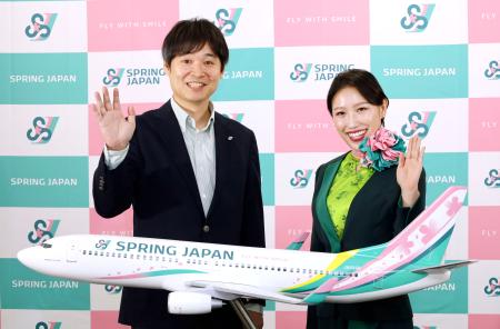 　新しいデザインの機体の模型と写真に納まる「スプリング・ジャパン」の浅見達朗社長（左）＝２６日午前、成田空港