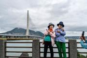 　台湾北部・淡水で淡江大橋を背景に記念撮影する人たち＝９日、新北市（共同）