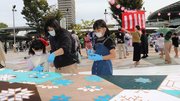 布の色づけ体験を楽しむ親子。広場にはやぐらが建てられ、郡上おどりの輪が広がった＝８日午前、岐阜市橋本町、信長ゆめ広場