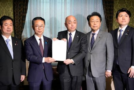 　政治資金規正法の改正案を衆院事務総長（中央）に提出する国民民主と公明両党の議員＝１９日午後、国会　