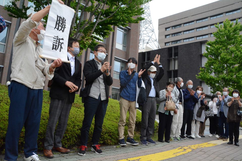 勝訴ののぼりを掲げて喜ぶ原告の住民ら＝１６日午後３時６分、岐阜地裁前