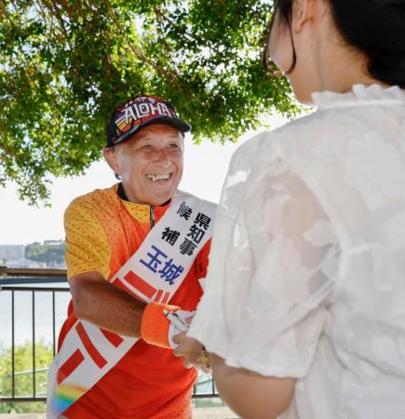 　街頭演説に集まった人と握手する玉城デニー氏＝１２日午後、那覇市