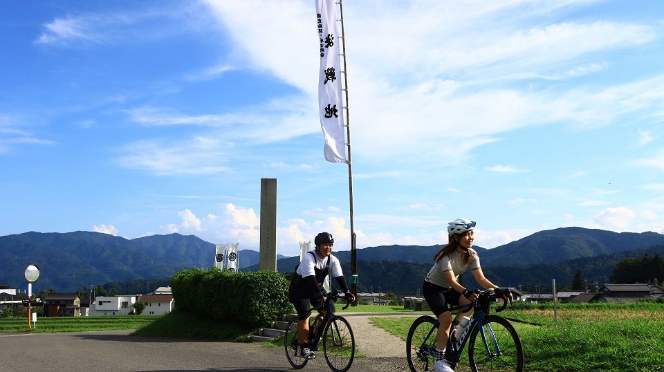 関ケ原古戦場決戦地の前を自転車で走る愛あむさん（手前右）ら参加者＝不破郡関ケ原町関ケ原