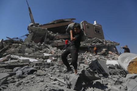 　イスラエルの攻撃を受けたビルのがれきから荷物を運び出す若者＝１２日、ガザ北部ガザ市（ＡＰ＝共同）