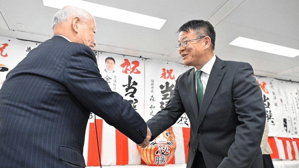 日置敏明市長と握手する山川弘保さん（右）＝３１日午後、岐阜県郡上市