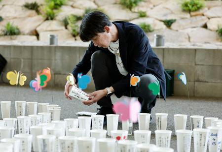 　尼崎ＪＲ脱線事故の追悼行事を前に、ろうそくを並べる上田誠さん＝２４日午後、兵庫県尼崎市
