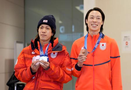 　羽田空港に到着し、メダルを手にするノルディックスキー・ジャンプ男子の二階堂蓮（左）と小林陵侑＝２０日午前