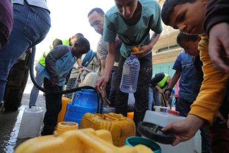 　１８日、ガザ中部ブレイジの難民キャンプで、水の配給を受ける人々（ゲッティ＝共同）