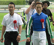 大勢のファンの声援を受け、表彰式に向かう寺島良調教師（左）と藤岡佑介騎手