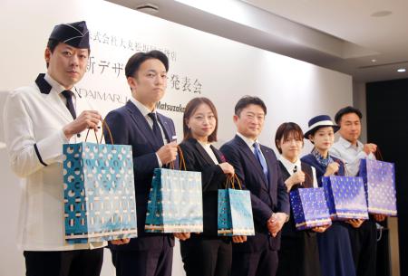 　大丸松坂屋百貨店の新しいショッピングバッグを持つ従業員ら＝１７日午前、東京都千代田区