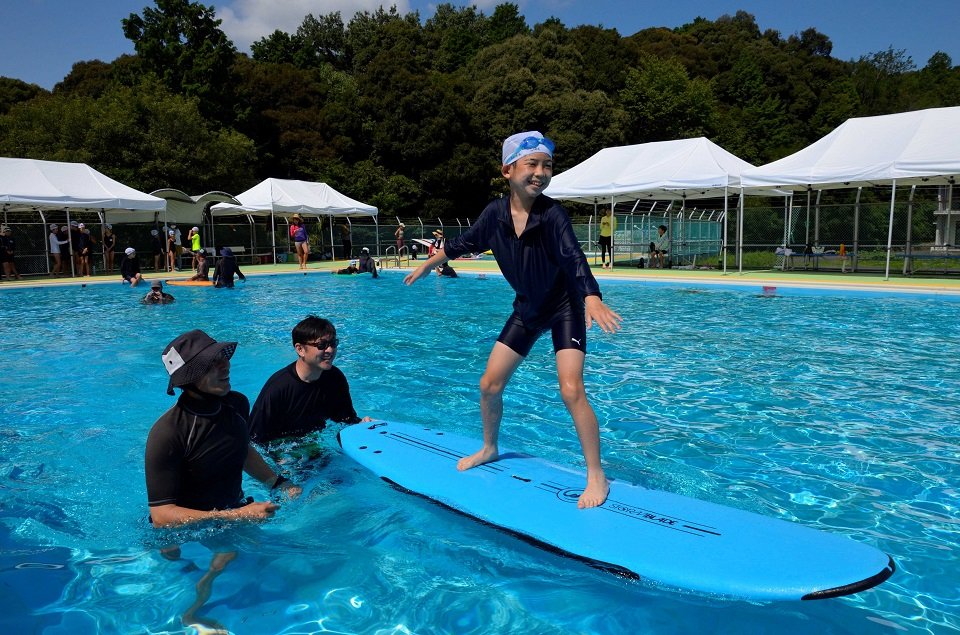 プールでサーフィンを楽しむ児童＝多治見市池田町、池田小学校
