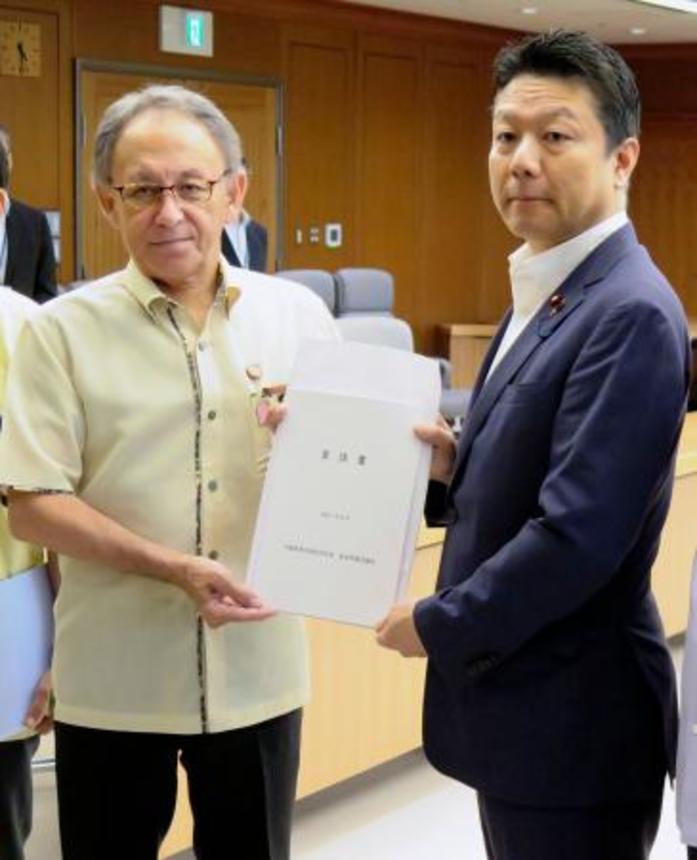 　本田太郎防衛副大臣（右）に要請書を手渡す沖縄県の玉城デニー知事＝２２日午後、防衛省