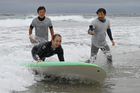 　障害者向けのサーフィン体験会で波に乗る片岡亮太さん＝３０日午前、福島県いわき市の薄磯海岸