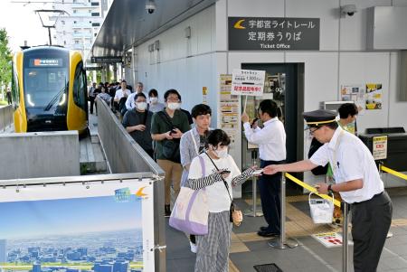 　累計利用者数が１５００万人を超えたＬＲＴ「ライトライン」の宇都宮駅東口停留所で行われた記念品の配布＝９日午後
