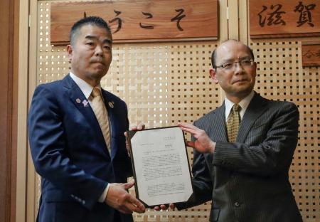 　滋賀県税制審議会から中間答申を受け取る三日月大造知事（左）＝４日午後、滋賀県庁