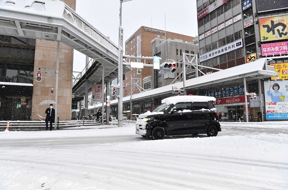 屋根に雪を乗せたまま雪道を走る車＝２４日午前７時４６分、岐阜市神田町