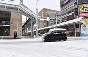 屋根に雪を乗せたまま雪道を走る車＝２４日午前７時４６分、岐阜市神田町