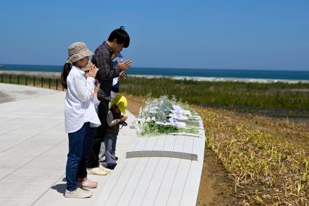 　福島県復興祈念公園で献花し、手を合わせる家族＝２日午後