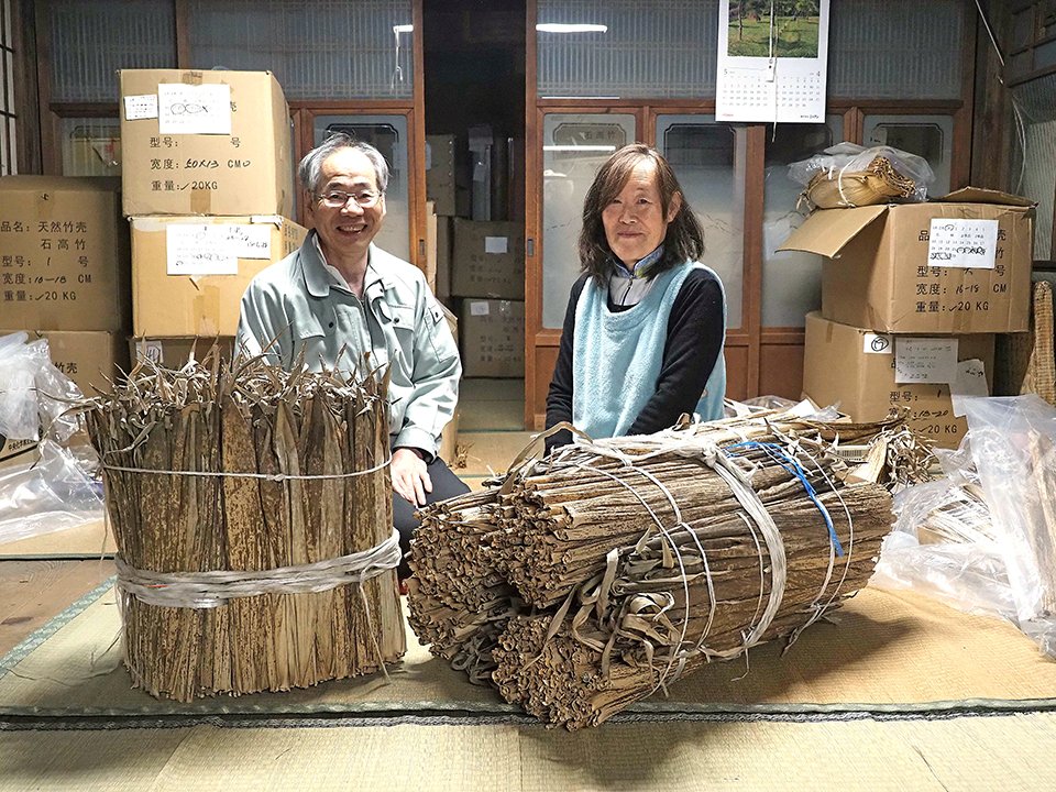 吉田包装店の吉田毅さんと鏡子さん。手前は水で戻す前の乾燥させた竹皮の束＝可児市