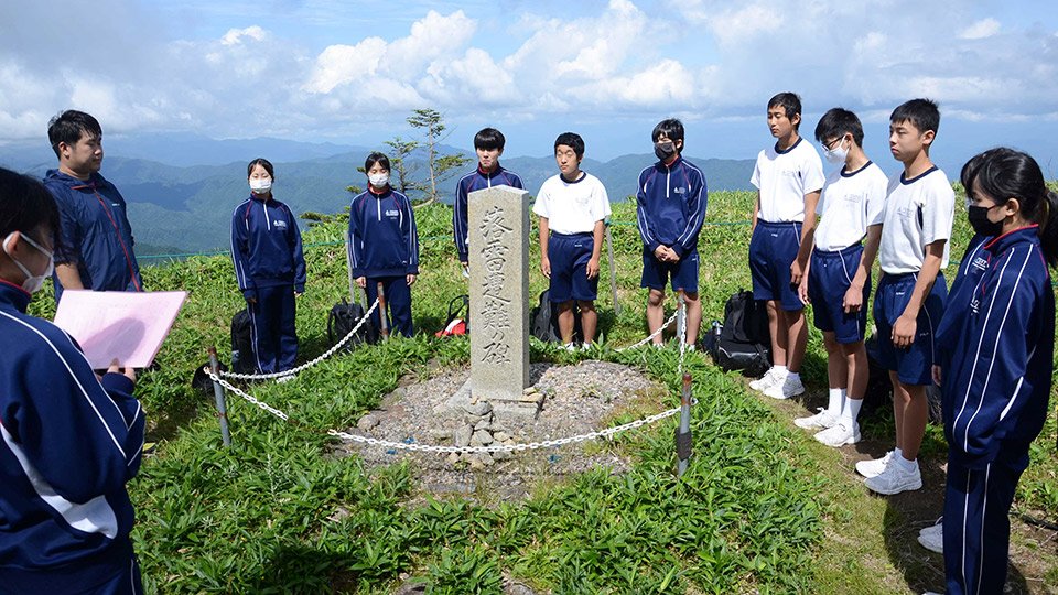 「落雷遭難の碑」の前で、１９５５年に落雷で亡くなった４人の先輩に思いを寄せる生徒ら＝長野県阿智村