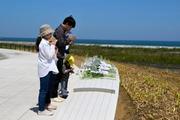 　福島県復興祈念公園で献花し、手を合わせる家族＝２日午後