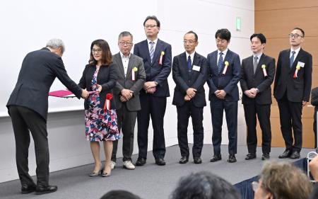 　日本写真協会賞の表彰式で、学芸賞の賞状を受け取る中国新聞社の金崎由美特別編集委員（左から２人目）と報道各社の代表者＝１日午後、東京都内