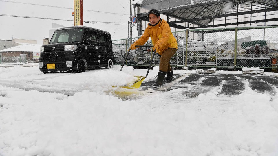 店の駐車場の雪をかく従業員＝８日午前８時３２分、岐阜市旦島中