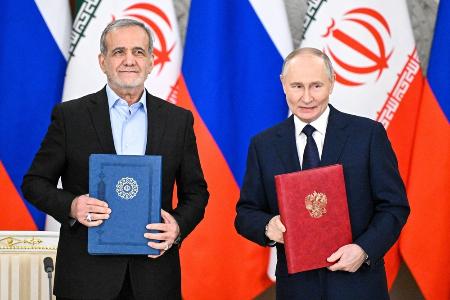 　昨年１月、包括的戦略パートナーシップ条約の署名式に臨むロシアのプーチン大統領（右）とイランのペゼシュキアン大統領＝モスクワ（タス＝共同）