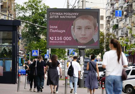 　２０２３年７月、子どもの捜索に取り組むＮＧＯが大型モニターに流した、行方不明者の情報提供を呼びかける広告＝キーウ中心部（共同）