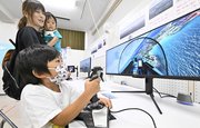 フライトシミュレーターを体験する子ども＝同