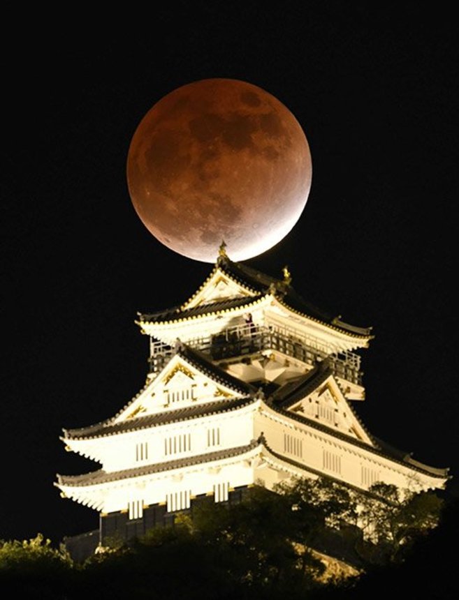 岐阜城の背後に浮かび上がった皆既食に近い赤銅色の月＝１９日午後６時１６分、岐阜市内