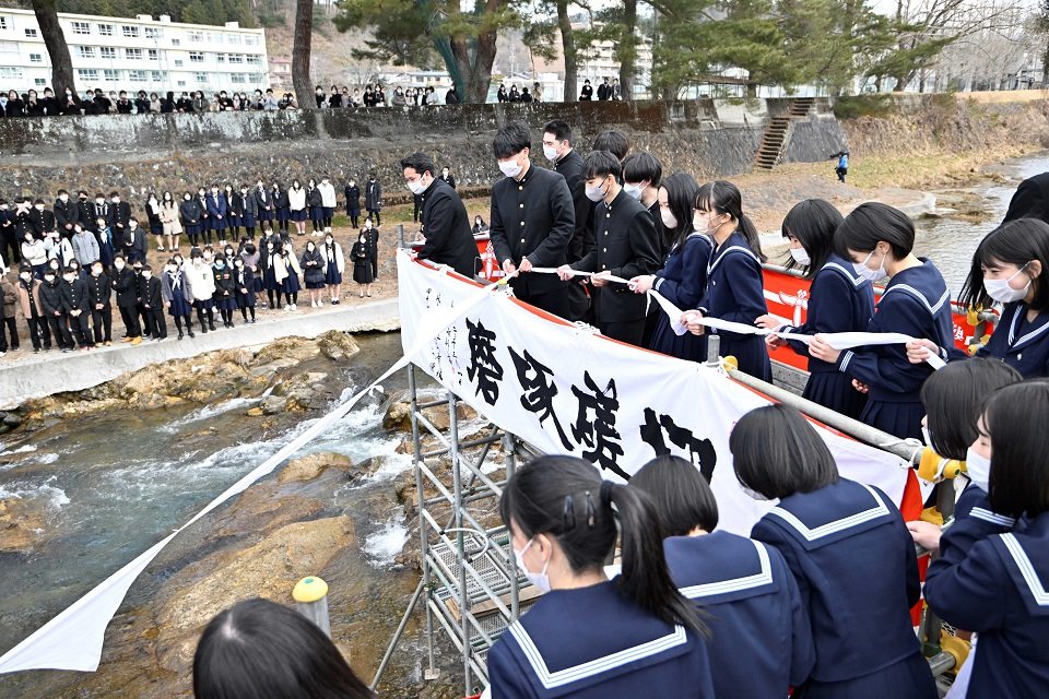 伝統の「白線流し」で結んだスカーフを流す卒業生ら＝１日午後１時２分、高山市大新町、大八賀川