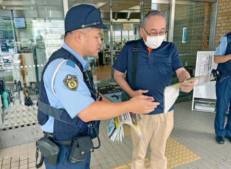 　公共施設の利用者（右）に住職刺殺事件の情報提供を呼びかける静岡県警細江署員＝１７日午前、浜松市