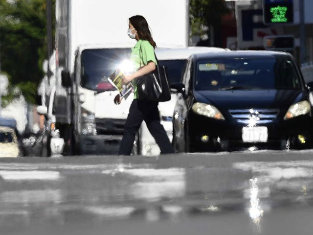 今季初の猛暑日になった岐阜市の交差点を歩く人＝１９日午後３時５５分、同市神田町