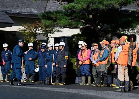 　クマに襲われたとみられる従業員が行方不明になった温泉旅館「瀬美温泉」で、捜索の準備をする警察官と猟友会のメンバー＝１７日午前、岩手県北上市