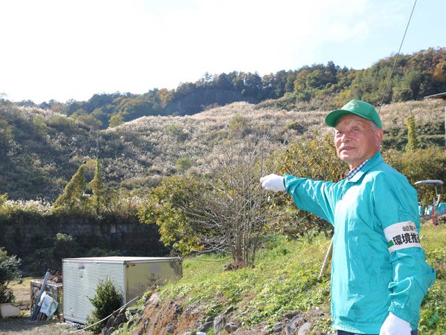 産業廃棄物の不法投棄現場を指さす増田実さん。現在は草が生い茂っている＝岐阜市椿洞
