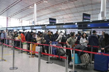 　春節に合わせた大型連休の初日、北京首都国際空港で日本便などをあつかうカウンターにならぶ人たち＝１５日（共同）