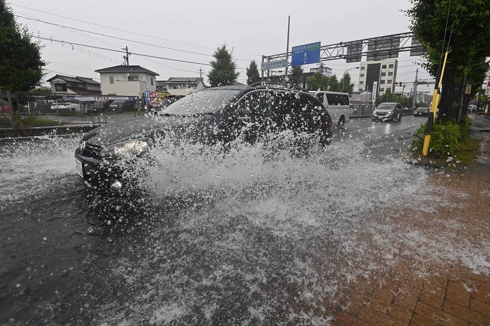 冠水した道をしぶきを上げて走る車＝２日午後１時４２分、多治見市白山町