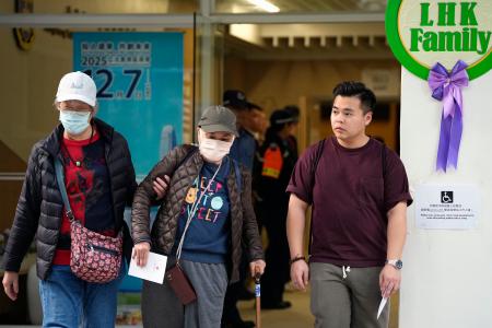 　立法会選挙の投票を終え、火災が起きた高層住宅群近くの投票所を出る有権者ら＝７日、香港（共同）