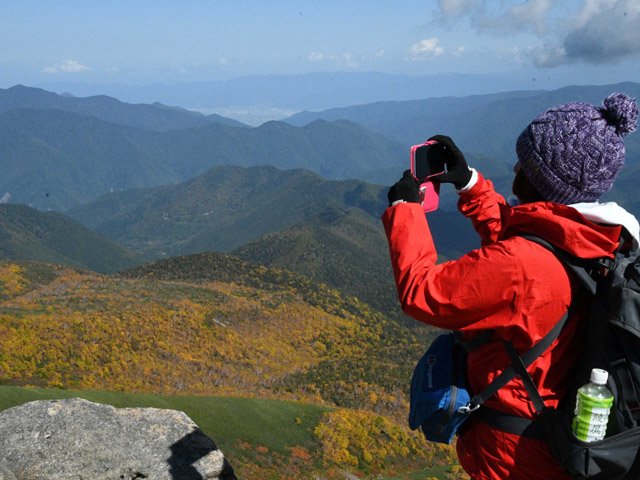 富士見岳頂上で紅葉を写真に収める登山者＝高山市丹生川町、乗鞍岳