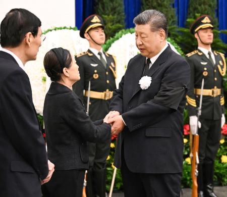 　中国の朱鎔基元首相の告別式に参列し、遺族（左）の手を握る習近平国家主席＝１８日、北京（新華社＝共同）