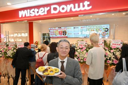 　上海のミスタードーナッツの店舗前で商品を手にするダスキンの大久保裕行社長＝２８日（共同）