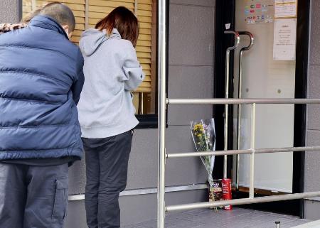 　現場となった店舗の出入り口に献花し、手を合わせる人＝昨年１２月、北九州市小倉南区