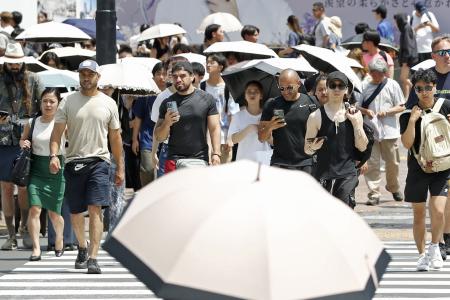 　東京・渋谷を歩く人たち。日傘を差す姿が目立った＝１８日午後